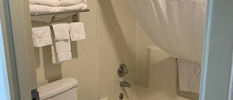 Un baño con inodoro, bañera y cortina de ducha.