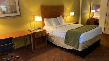 A hotel room with a bed, bedside tables, a desk, a chair, and a framed picture on the wall.