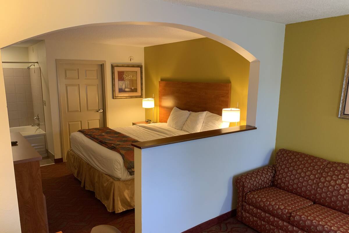 Una habitación de hotel con cama, sofá, escritorio y baño.