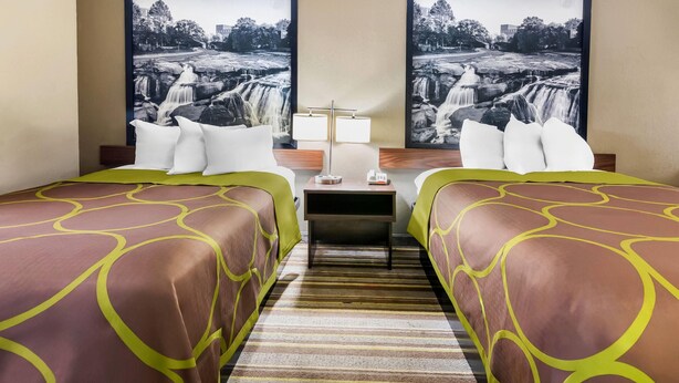 A hotel room with two beds, a nightstand, a lamp, and two large black-and-white waterfall paintings on the wall. - Super 8 by Wyndham Columbia (Columbia)