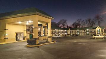 A motel with a gas station attached, featuring a large parking lot and a building with multiple windows.