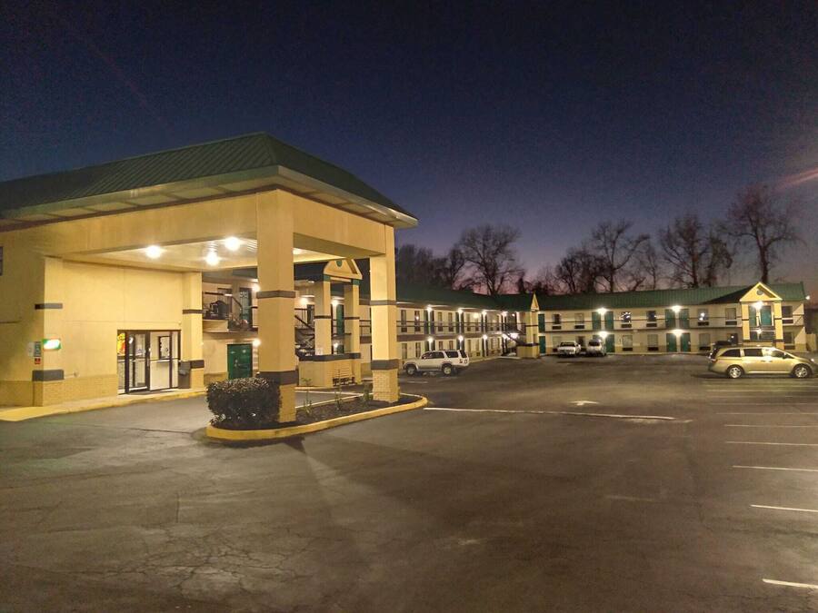 A motel with a gas station attached, featuring a large parking lot and a building with multiple windows.