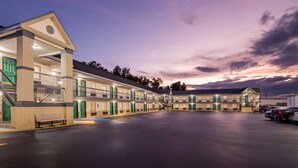 A motel with multiple units, a covered parking area, and a staircase leading to the entrance. - Super 8 by Wyndham Columbia (Columbia)