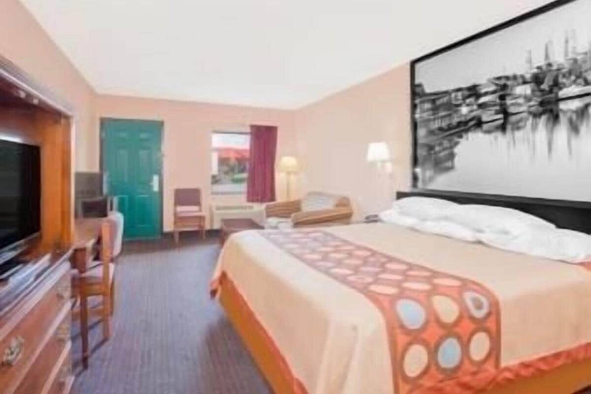 A hotel room with a bed, a television, a desk, and a chair.