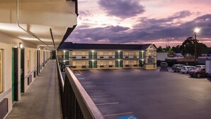 A motel with a covered walkway, a parking lot, and a building with multiple doors and windows. - Super 8 by Wyndham Columbia (Columbia)