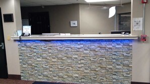 A reception desk with a stone-textured counter, a fire extinguisher, and a QR code on the wall. - Super 8 by Wyndham Columbia (Columbia)