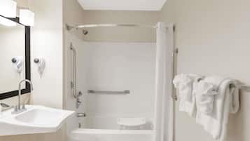 A modern bathroom with a sink, mirror, shower, and bathtub.