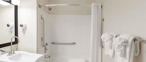 A modern bathroom with a sink, mirror, shower, and bathtub.