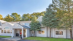 A two-story house with a garage, a covered porch, and a large evergreen tree in front. - Super 8 by Wyndham Schenectady/Albany Area (Schenectady)