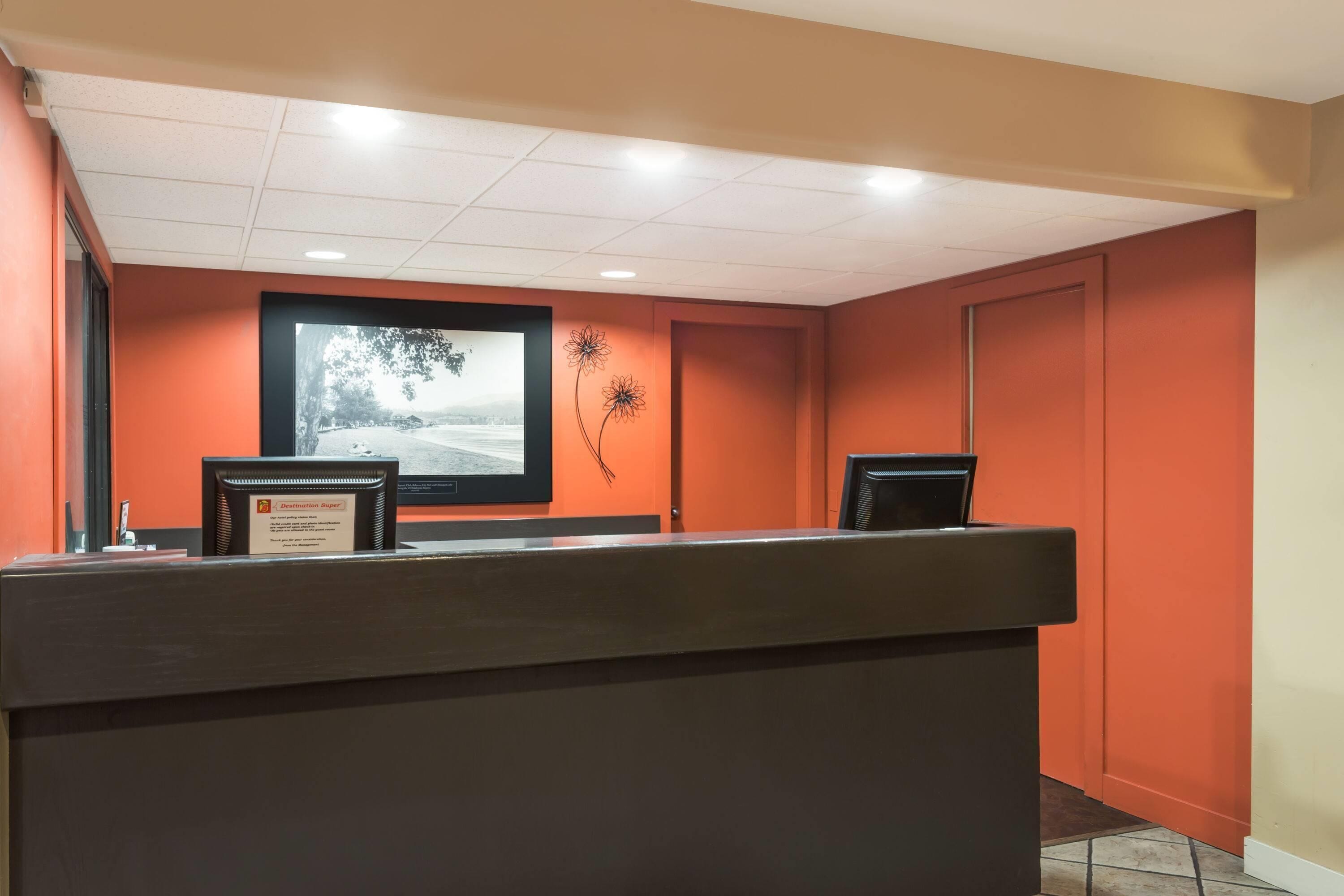 A reception desk with a framed picture of a landscape, a framed certificate, and a wall-mounted flower decoration.