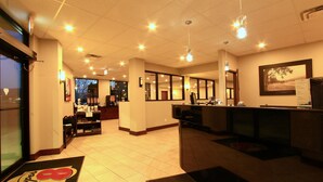 Een hotel lobby met een receptiebalie, een koffieapparaat en een groot raam.