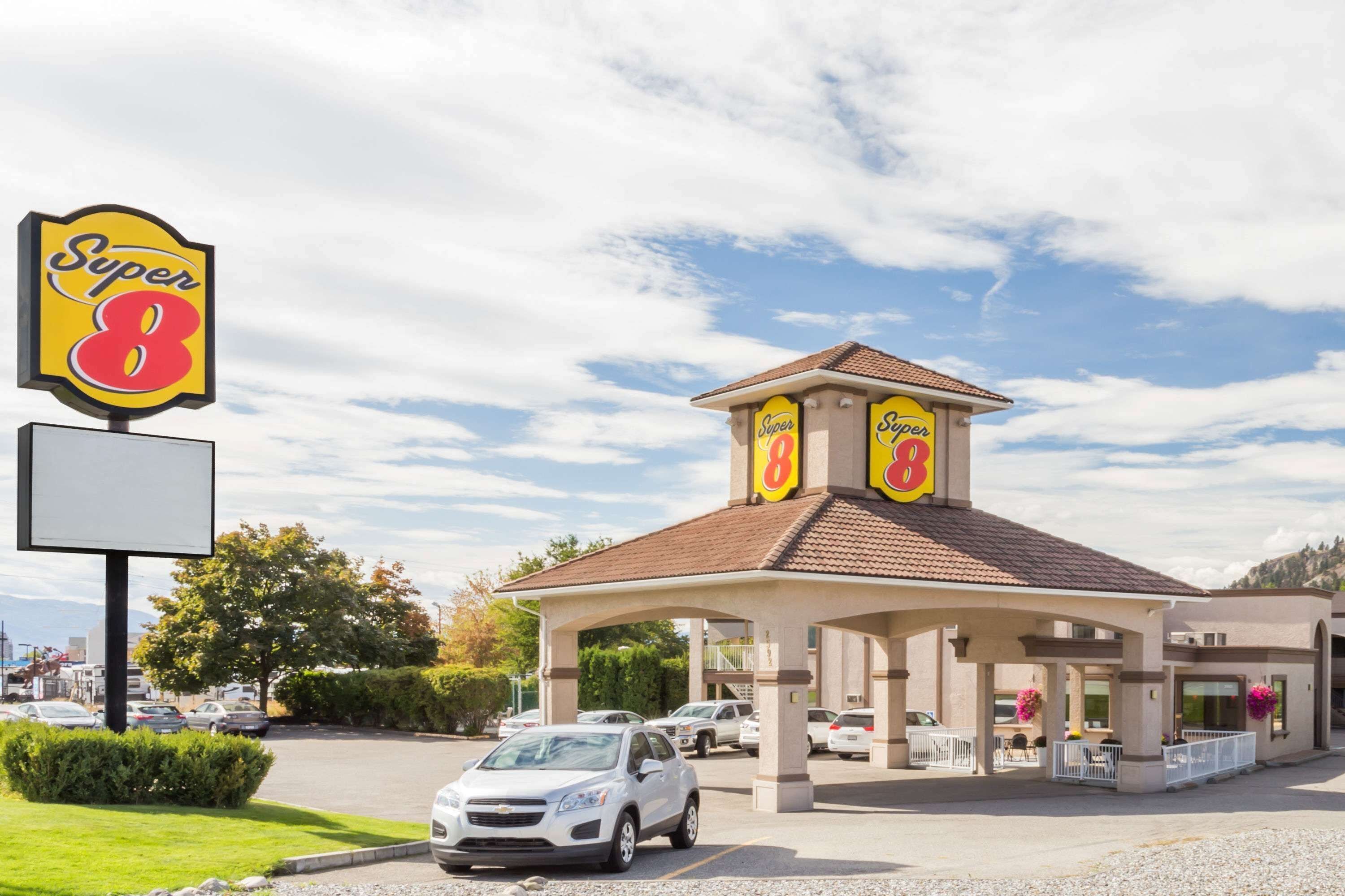 A Super 8 hotel with a central building and a parking lot.