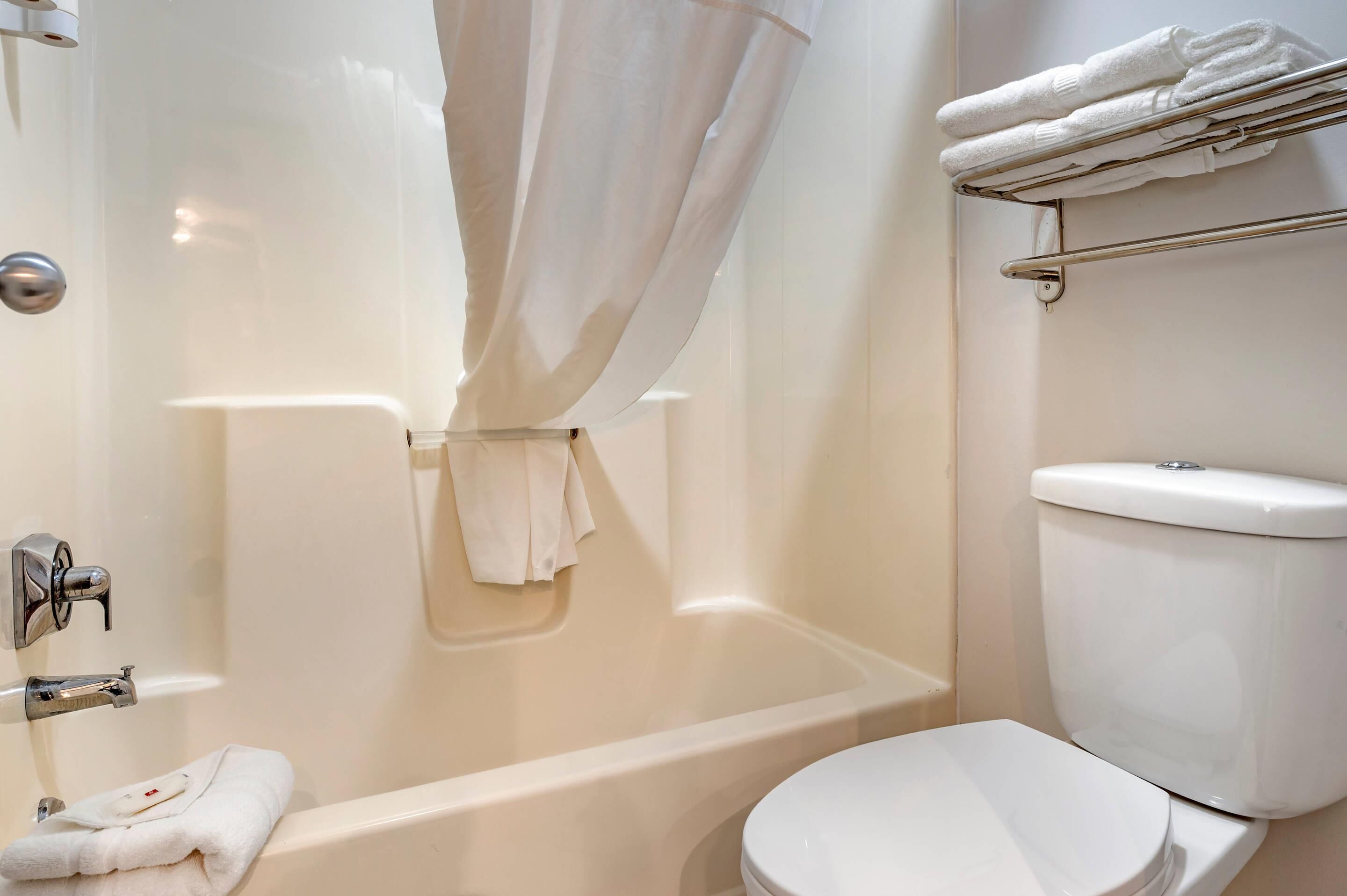 Een badkamer met een bad, toilet en een handdoekhouder.