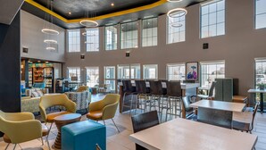 A spacious indoor area with multiple seating arrangements, including tables and chairs, and a counter area with a refrigerator and other amenities.