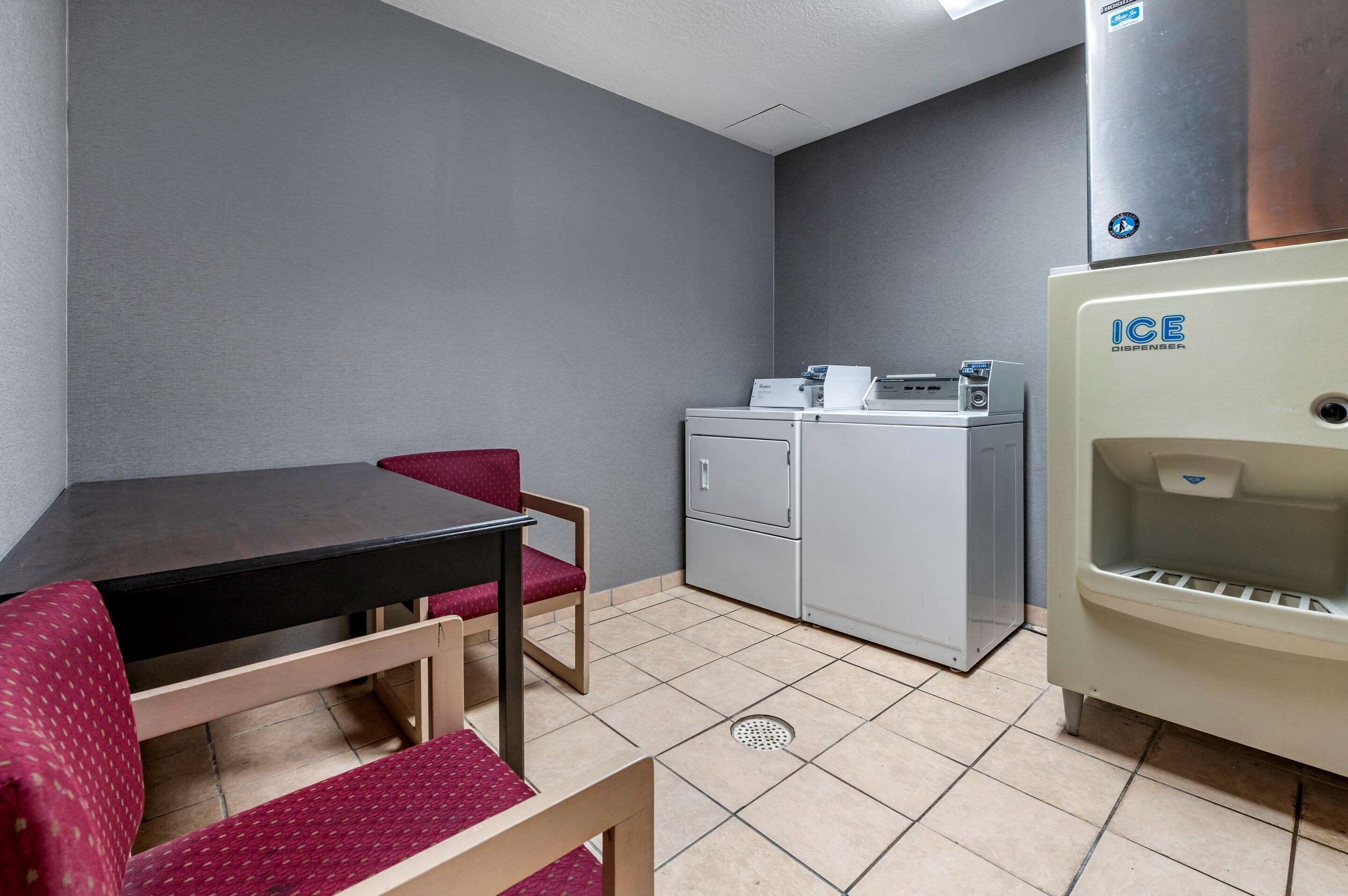 A compact kitchenette with a grey refrigerator, a coffee machine, and a small sink.