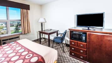 A hotel room with a bed, a desk, a chair, a television, a microwave, and a dresser.