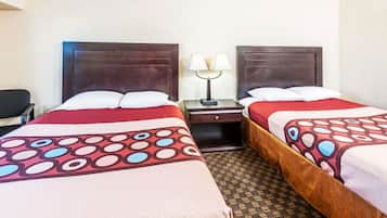 Habitación de hotel con dos camas, cada una con cabecera de madera, mesita de noche y lámpara, y alfombra estampada.