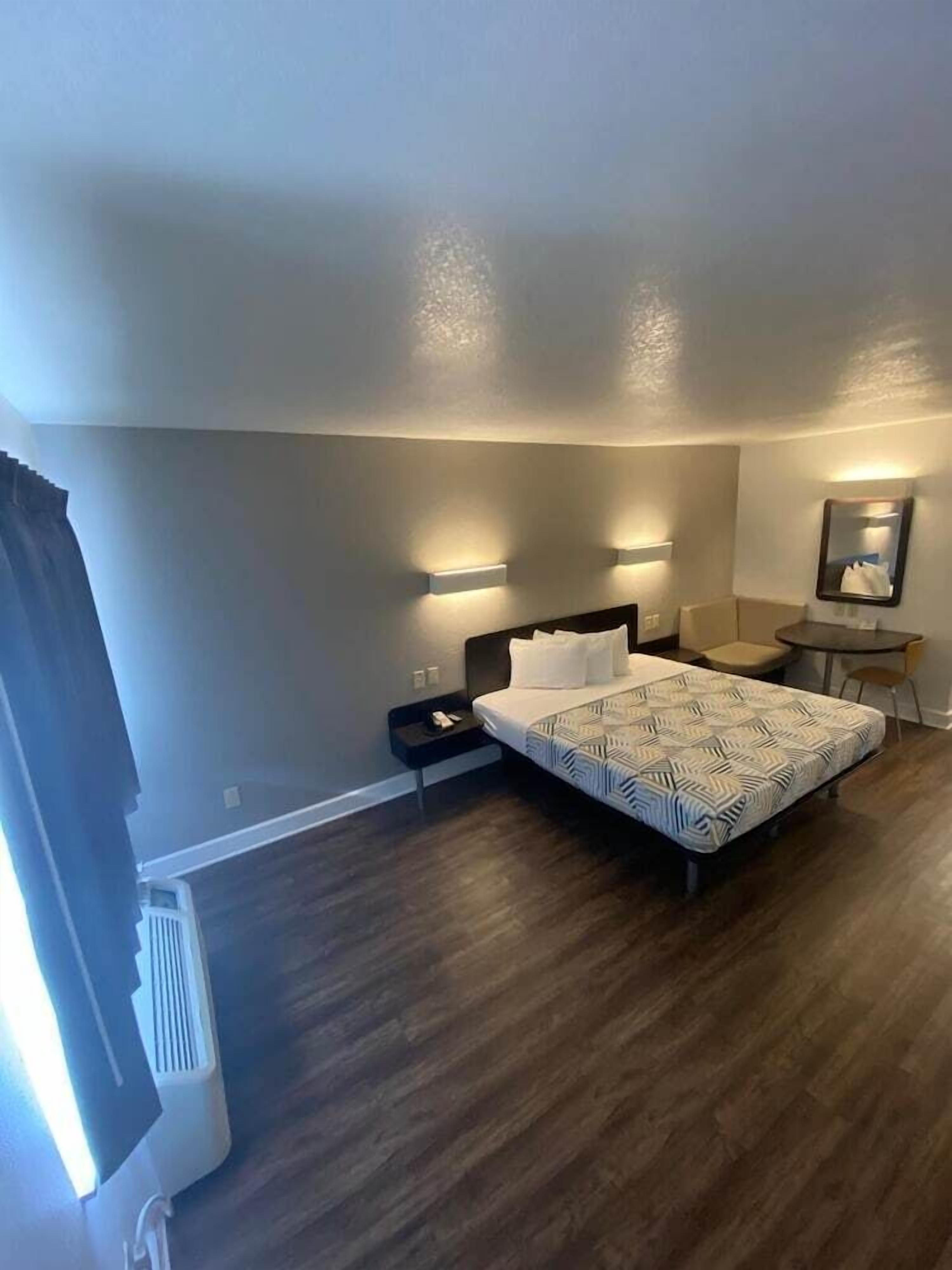 A bedroom with a bed, bedside tables, a desk, and a chair.