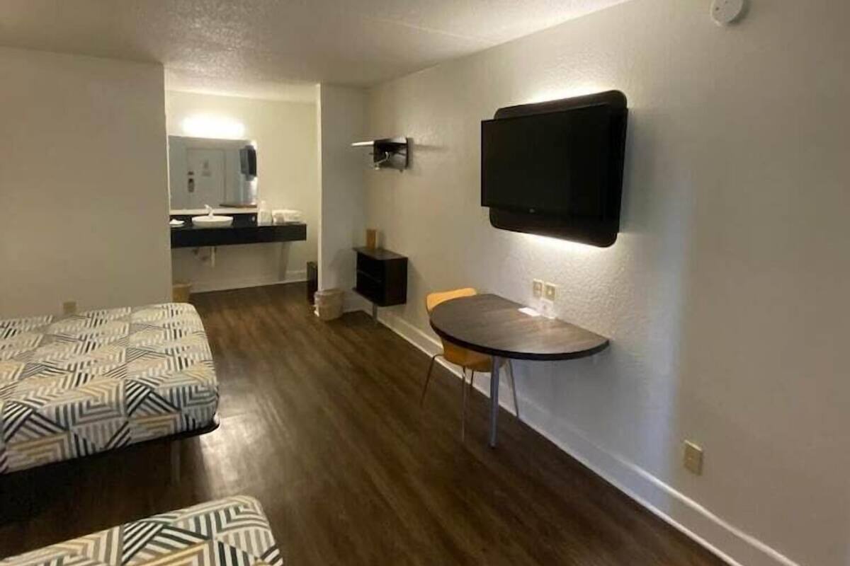 A compact living space with a kitchenette, a dining area with a table and chairs, and a patterned sofa.