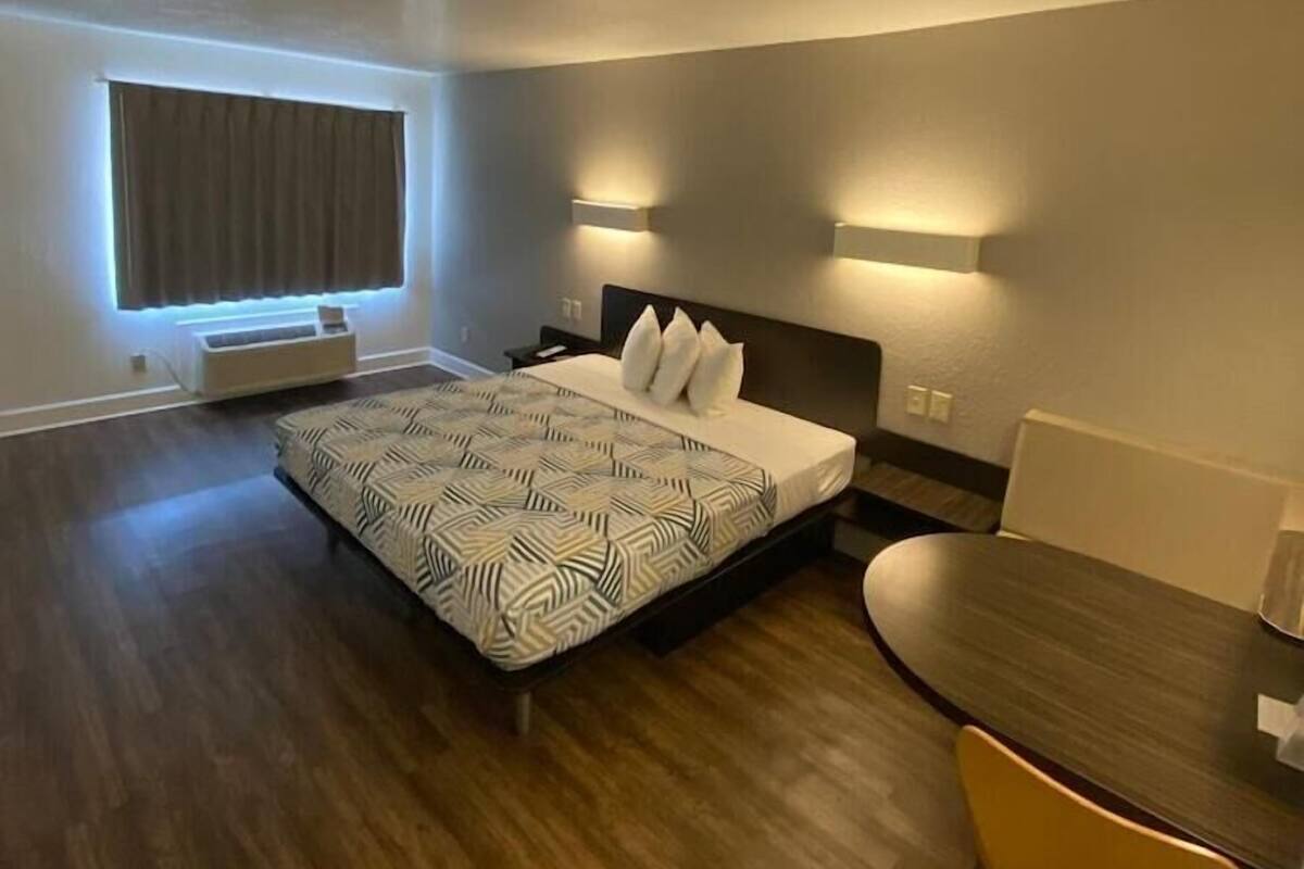 A hotel room with a bed, bedside tables, a desk, and a chair.
