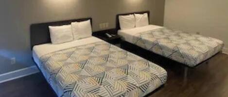 Une chambre avec deux lits, chacun recouvert d’une couvre-lit à motifs, et deux appliques murales.