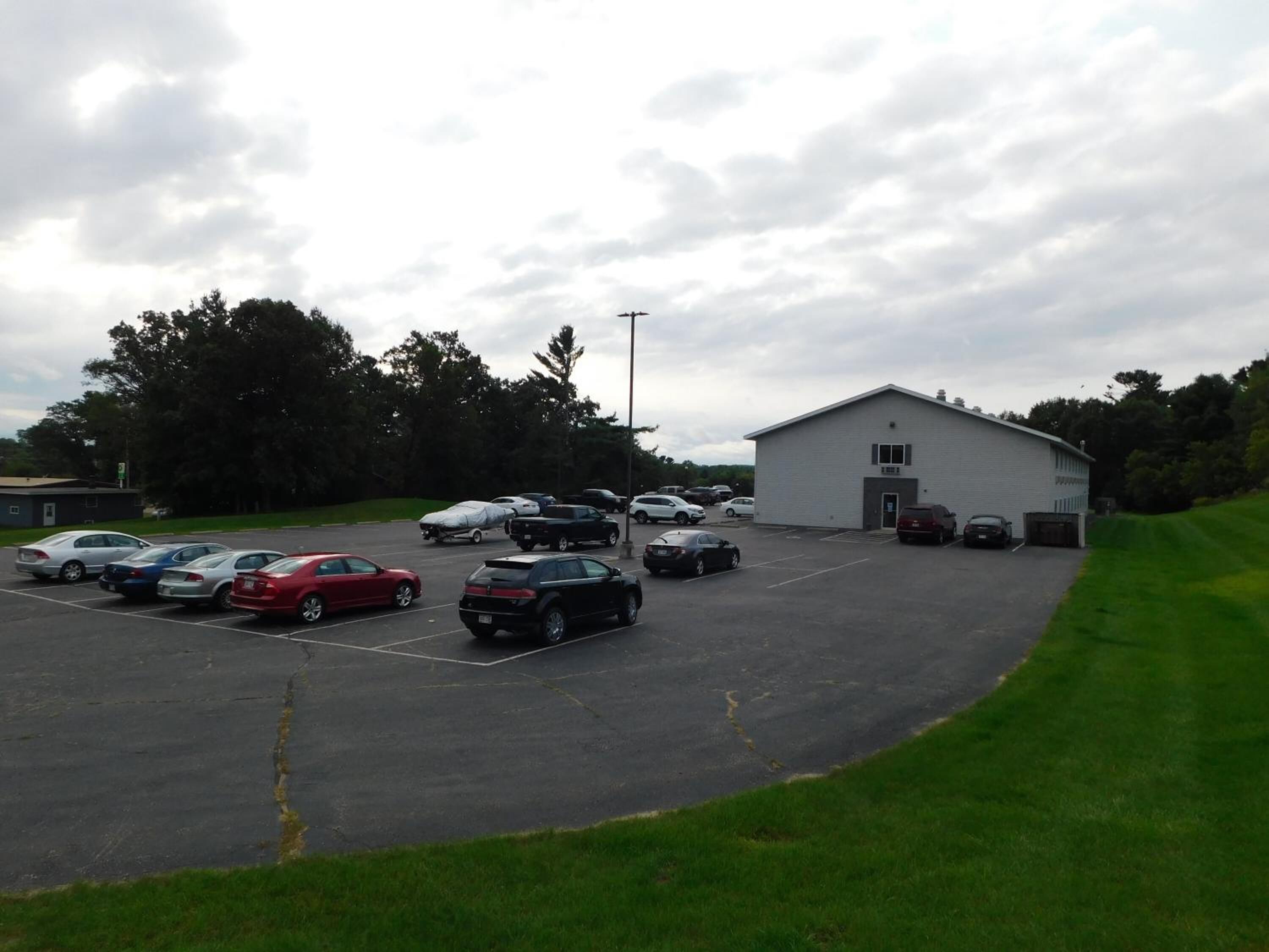 A parking lot with several cars and a building with a flat roof.