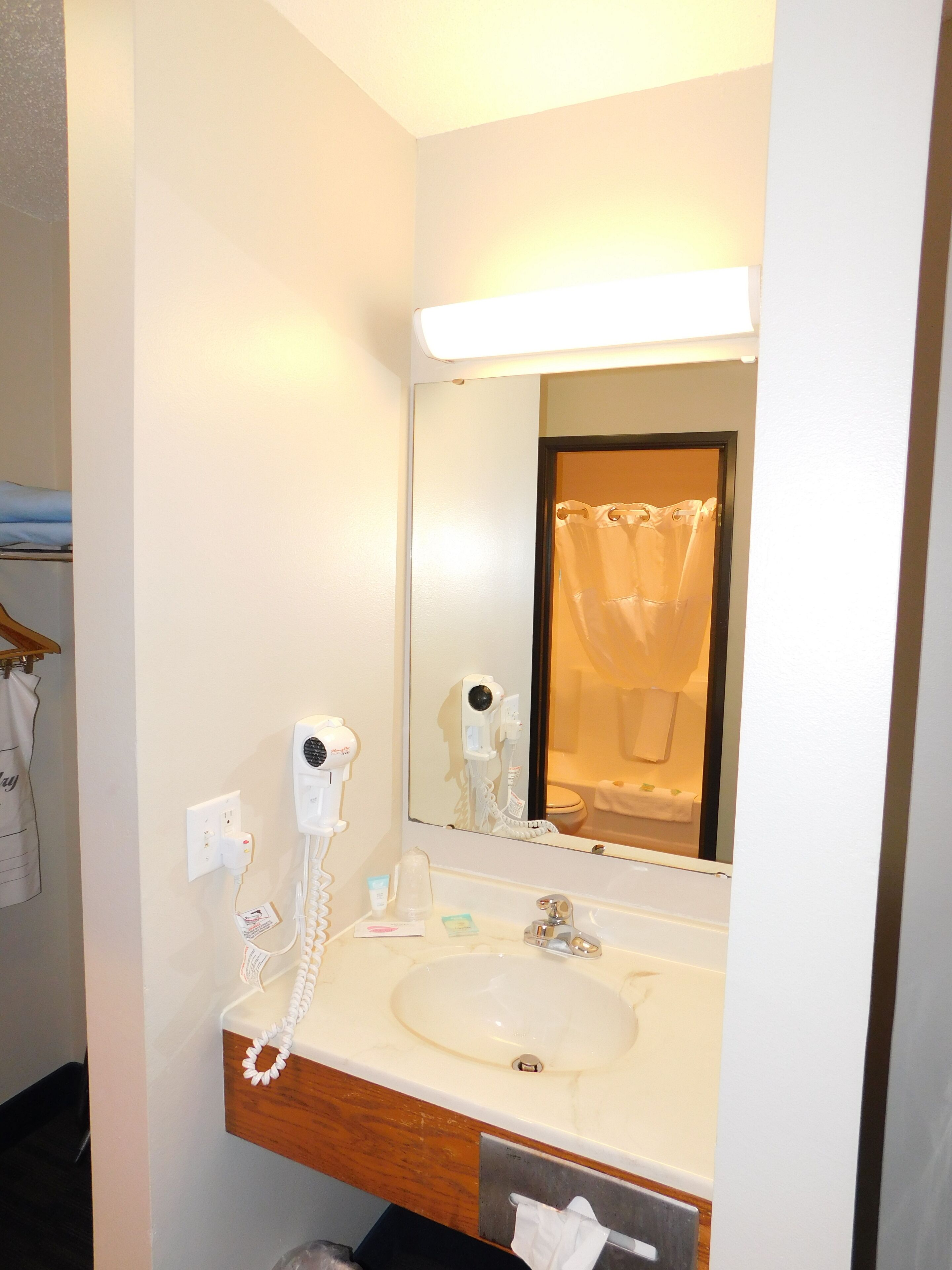 A hotel bathroom with a sink, mirror, and hairdryer.