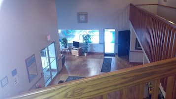 A spacious living area with a wooden staircase, a television, and a potted plant.