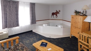 Ett rum med ett stort badkar, ett träskåp, ett bord med en bok och en mönstrad soffa.