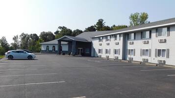 Un motel con estacionamiento techado y un edificio de dos pisos con múltiples ventanas.