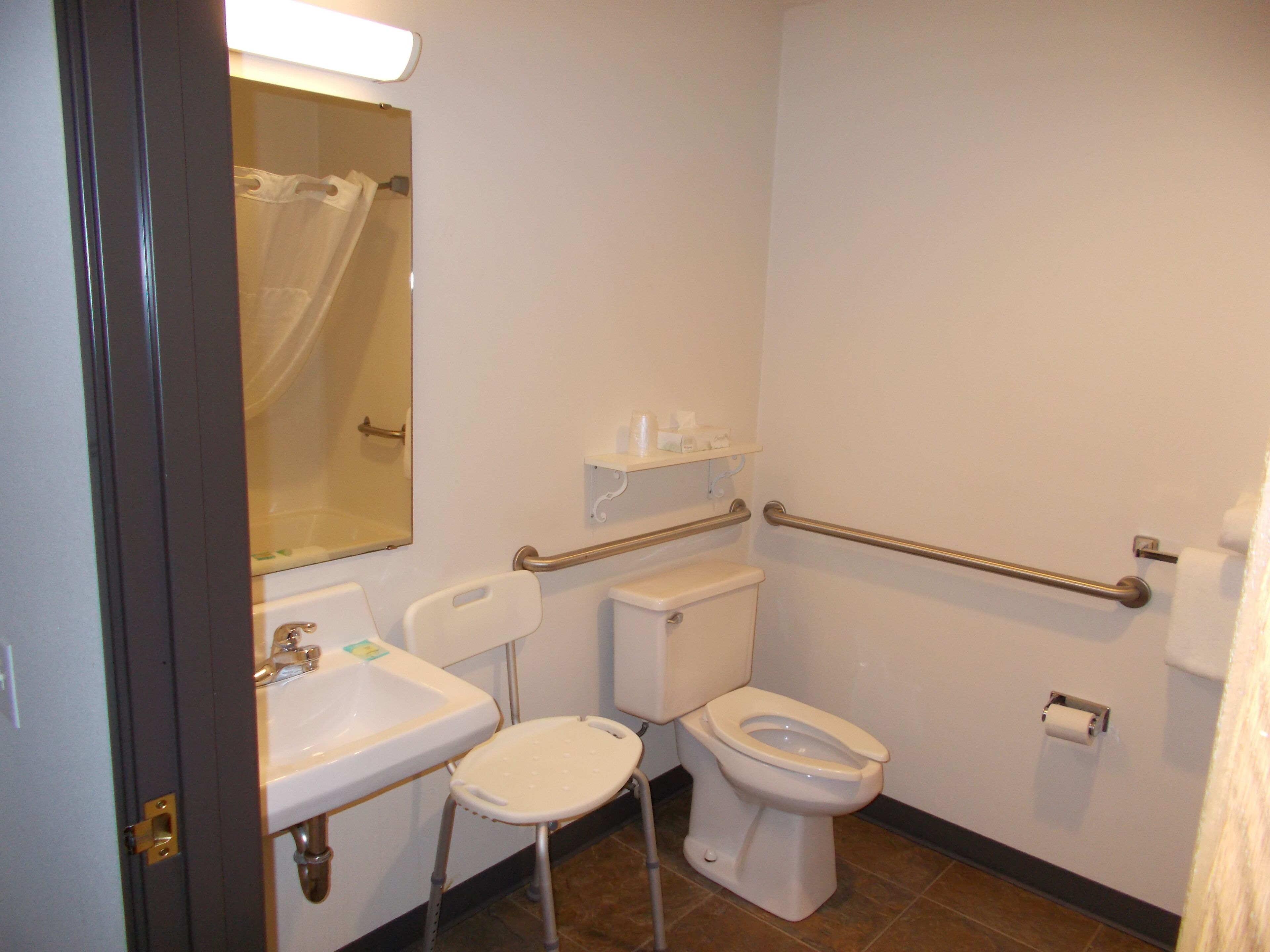 A bathroom with a toilet, sink, and a mirror. There is a shower curtain visible in the background.
