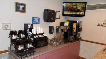 A hotel kitchen with coffee machines, a microwave, and a coffee dispenser.