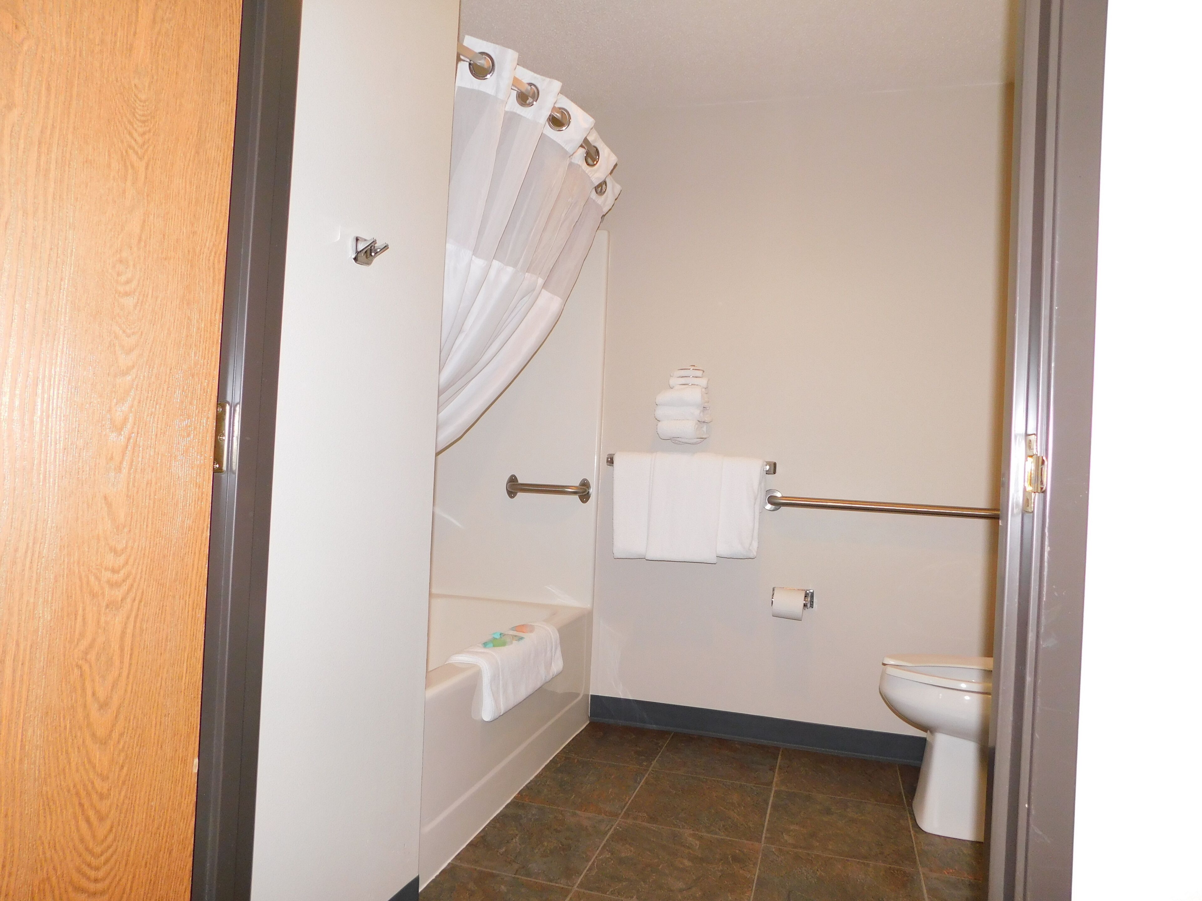 A bathroom with a bathtub, toilet, and shower curtain.