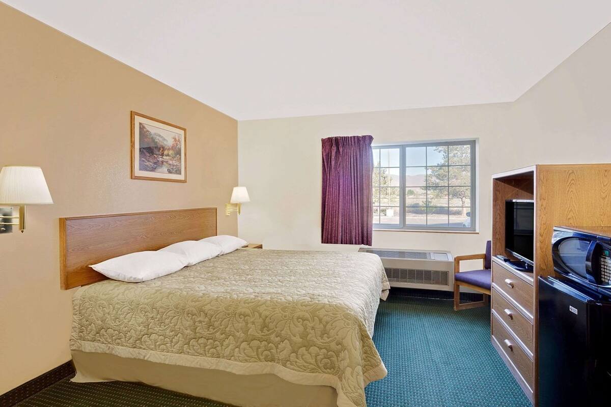 Een hotelkamer met een bed, een bureau, een televisie en een raam.