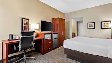 A hotel room with a bed, desk, chair, television, and wardrobe.