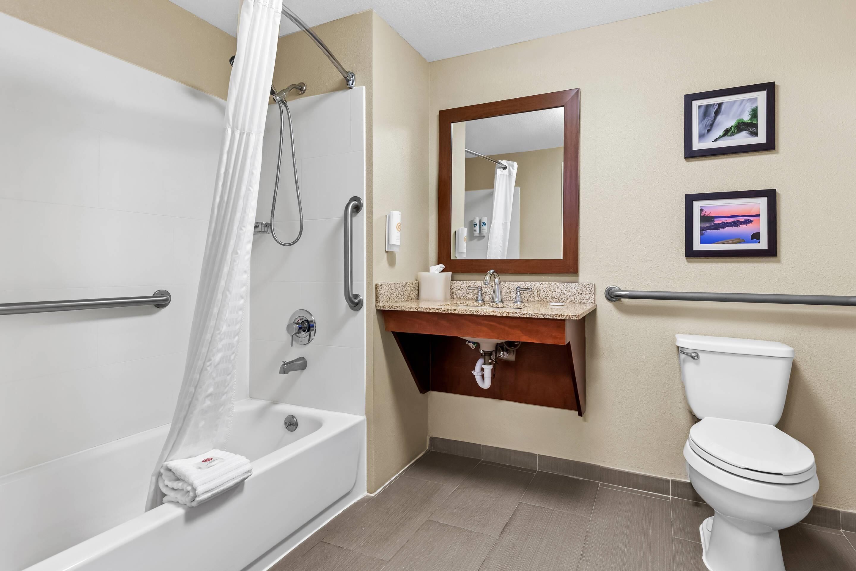 Un baño con bañera, lavamanos con espejo e inodoro.
