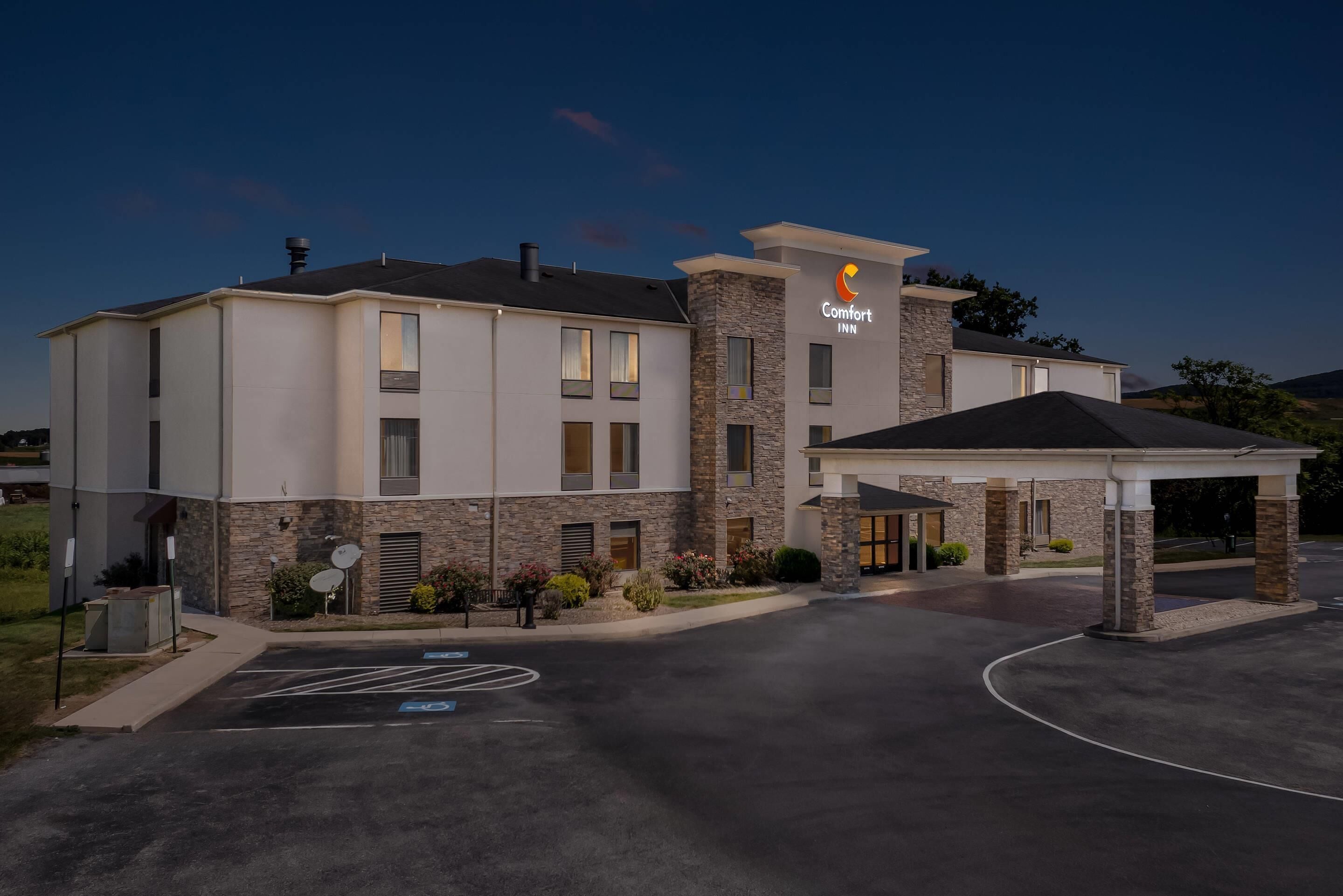 Un hotel Comfort Inn con un diseño moderno, que presenta fachada de piedra, ventanas amplias y una zona de entrada cubierta.