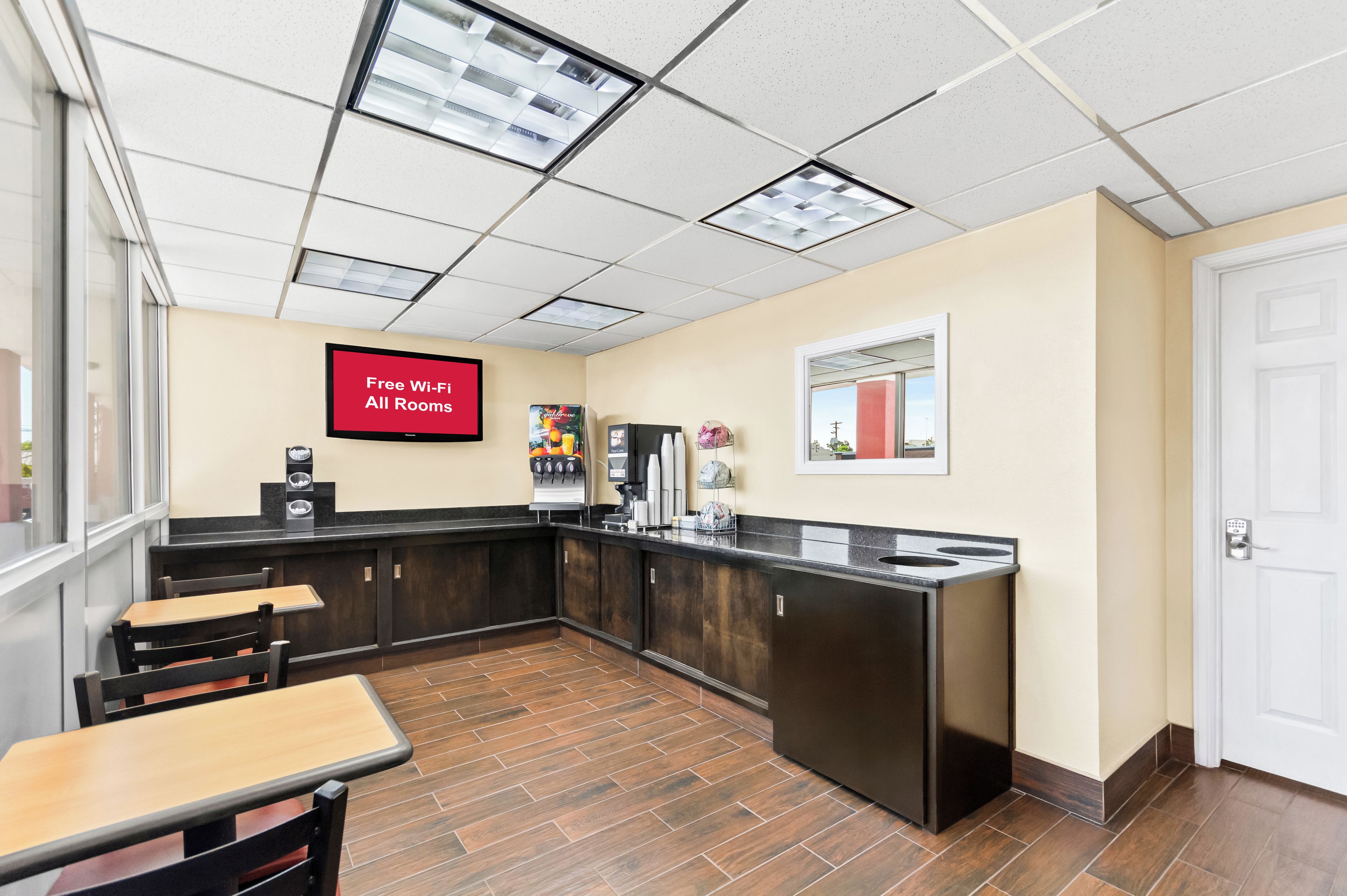 A hotel lobby with a kitchenette area, a coffee machine, and a sign indicating free Wi-Fi in all rooms.