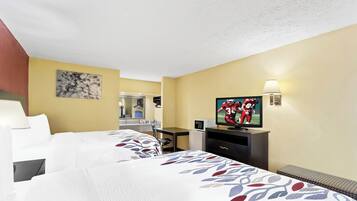 A hotel room with two beds, a desk, a television, and a mirror.