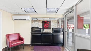 A reception area with a red leather chair, a black reception desk, and a Red Roof Inn sign.