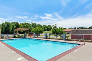 A clear blue swimming pool with a wooden deck area, a covered seating area, and a fenced poolside. - Red Roof Inn Berea (Berea)
