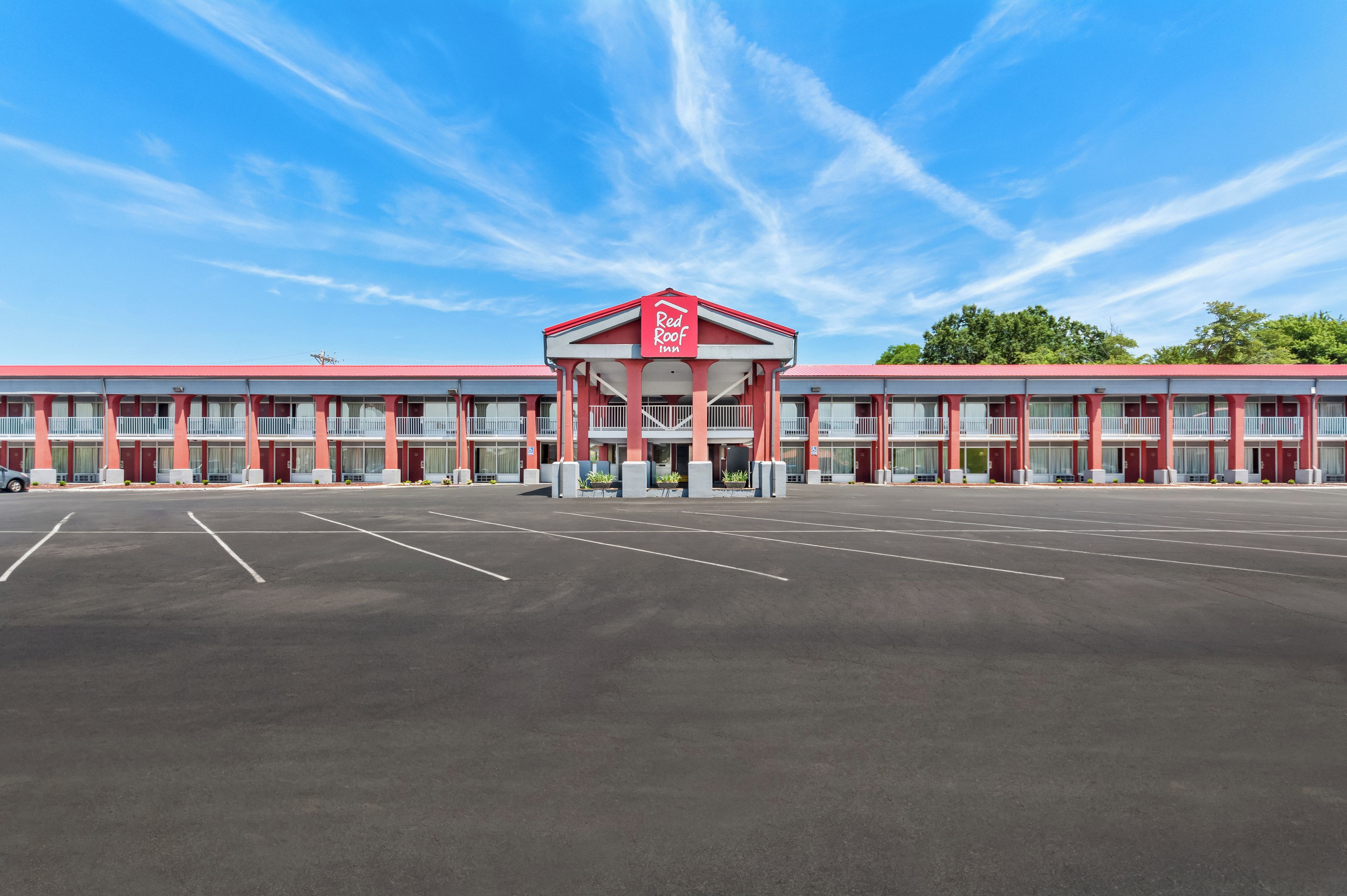 A motel with a central red sign, multiple balconies, and a parking lot.