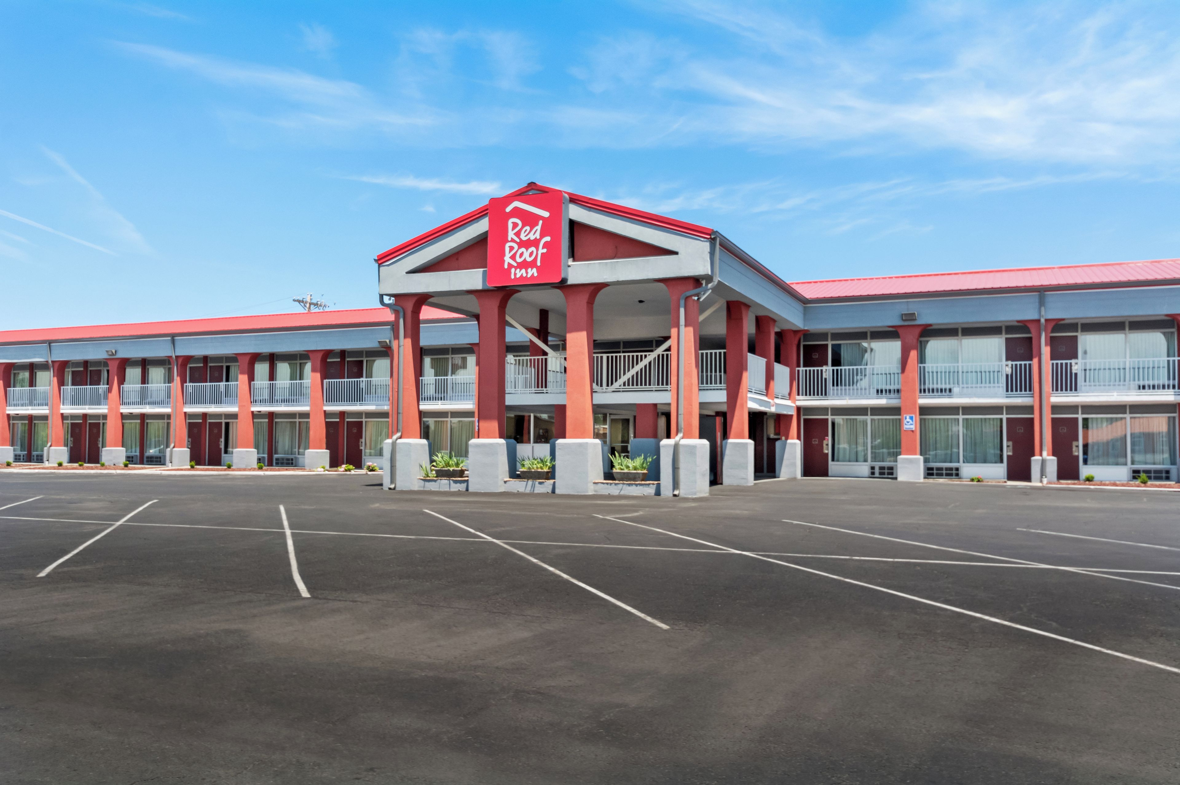 A Red Roof Inn with a central entrance, multiple balconies, and a parking lot.