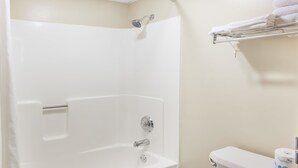 A bathroom with a white bathtub, a toilet, and a towel rack with folded towels.