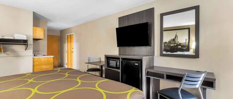A hotel room with a large bed, a desk with a chair, a television, and a microwave.