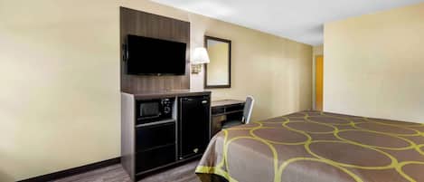 A hotel room with a bed, a desk with a chair, a television, and a microwave.