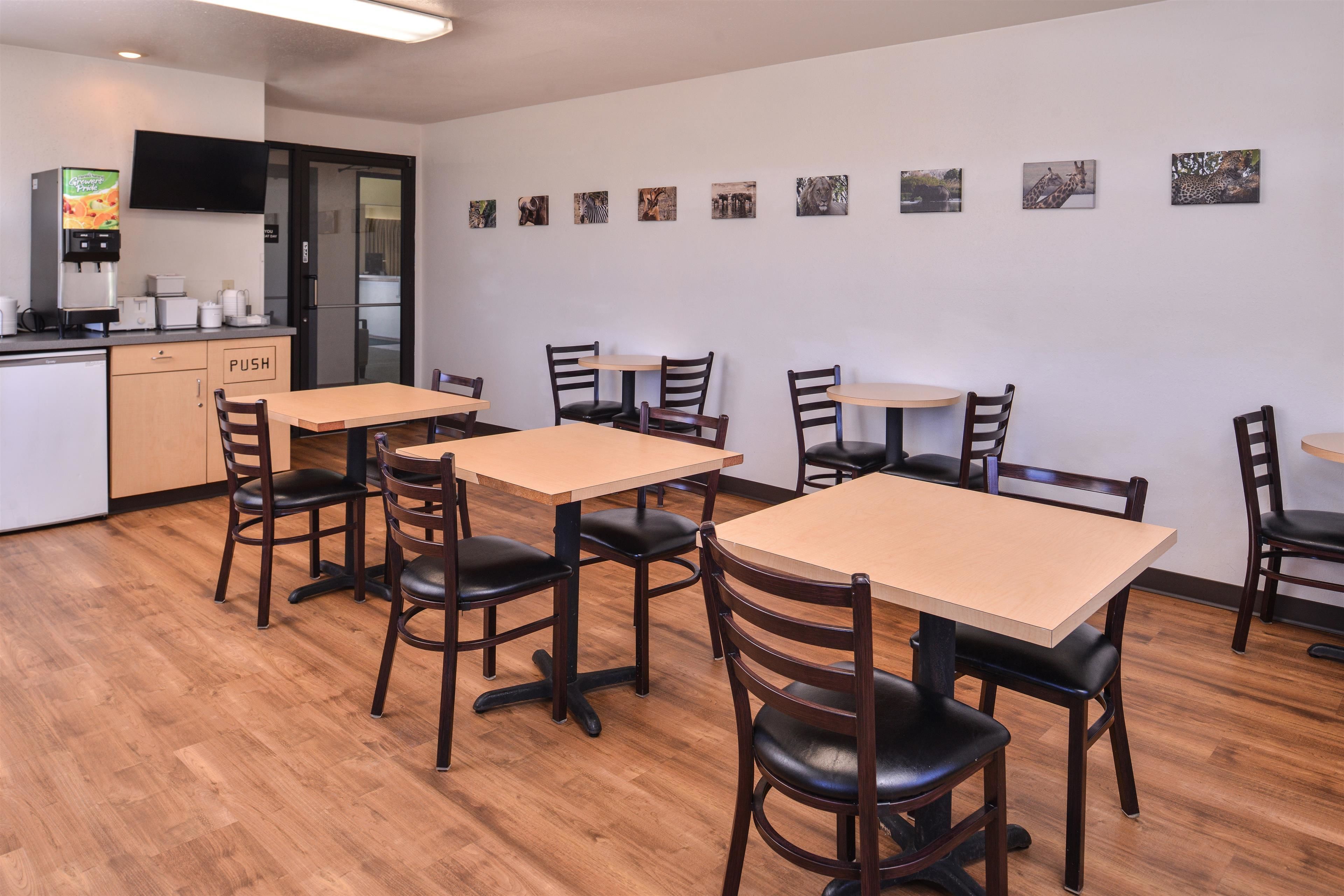 A restaurant with wooden tables and chairs, a kitchen area, and wall-mounted pictures of animals.