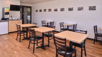 A restaurant with wooden tables and chairs, a kitchen area, and wall-mounted pictures of animals.