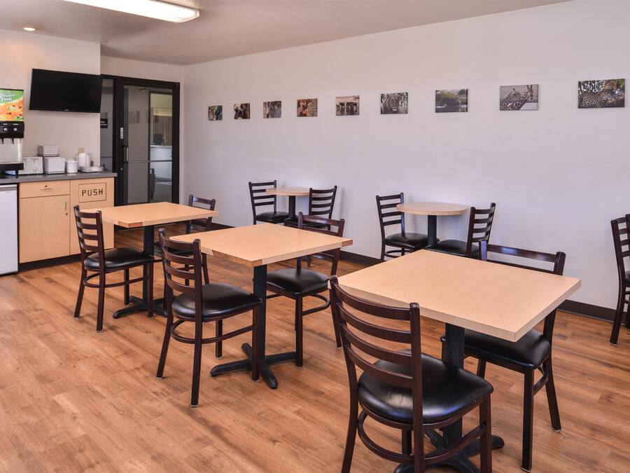 A restaurant with wooden tables and chairs, a kitchen area, and wall-mounted pictures of animals.