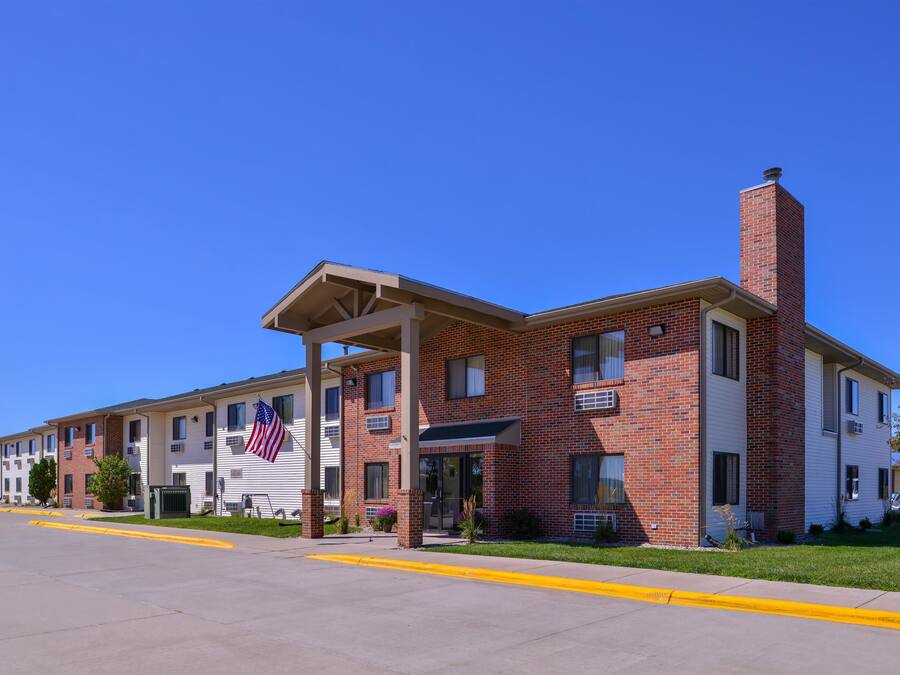 A multi-story building with a brick facade, a covered entrance, and an American flag.